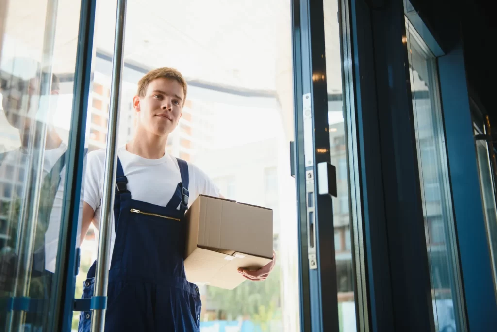 delivery man carrying box through revolving door utc