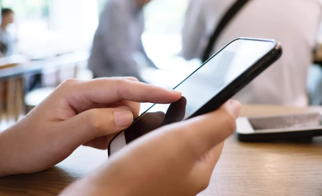 hands using mobile phone in bright office setting utc