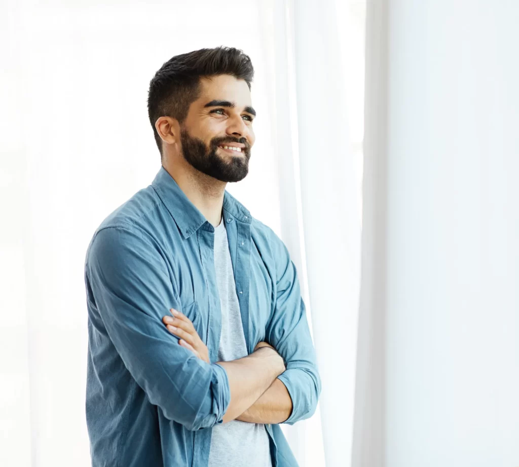 smiling man with arms crossed near window utc