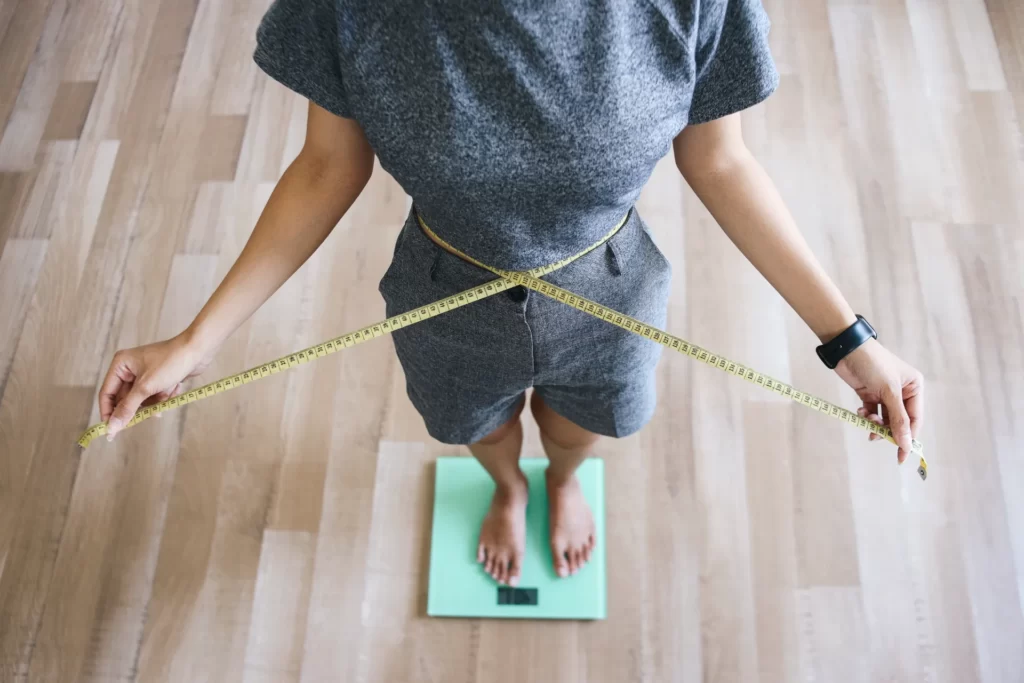 woman measures waist while standing on scale utc ()
